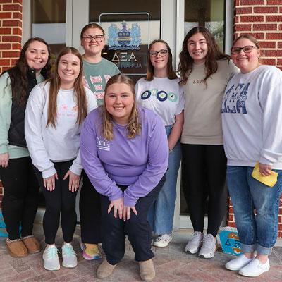 students pose outside the door of armstrong hall